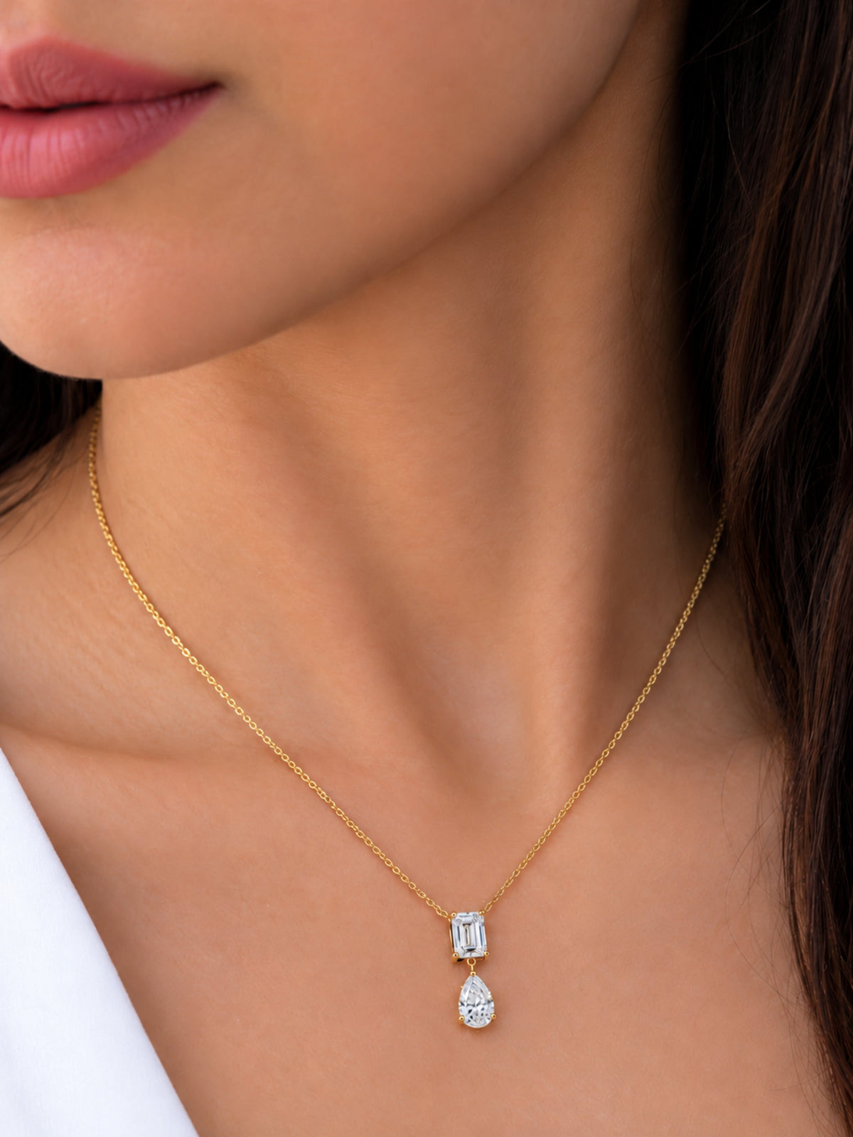 Emerald cut and pear lab diamond pendant necklace worn on neck